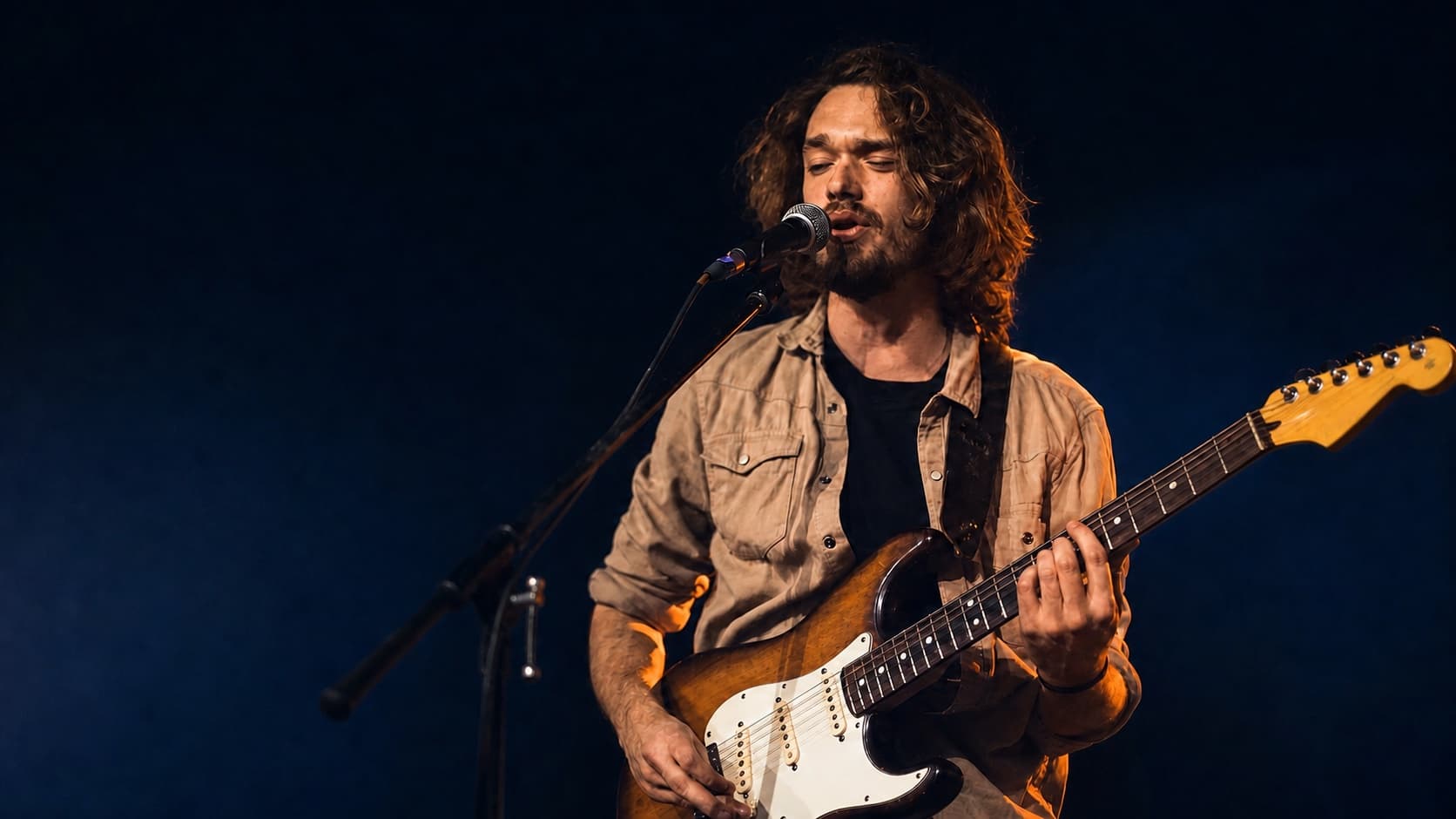 Erwachsener Gitarrist spielt eine E-Gitarre konzentriert auf einer Bühne
