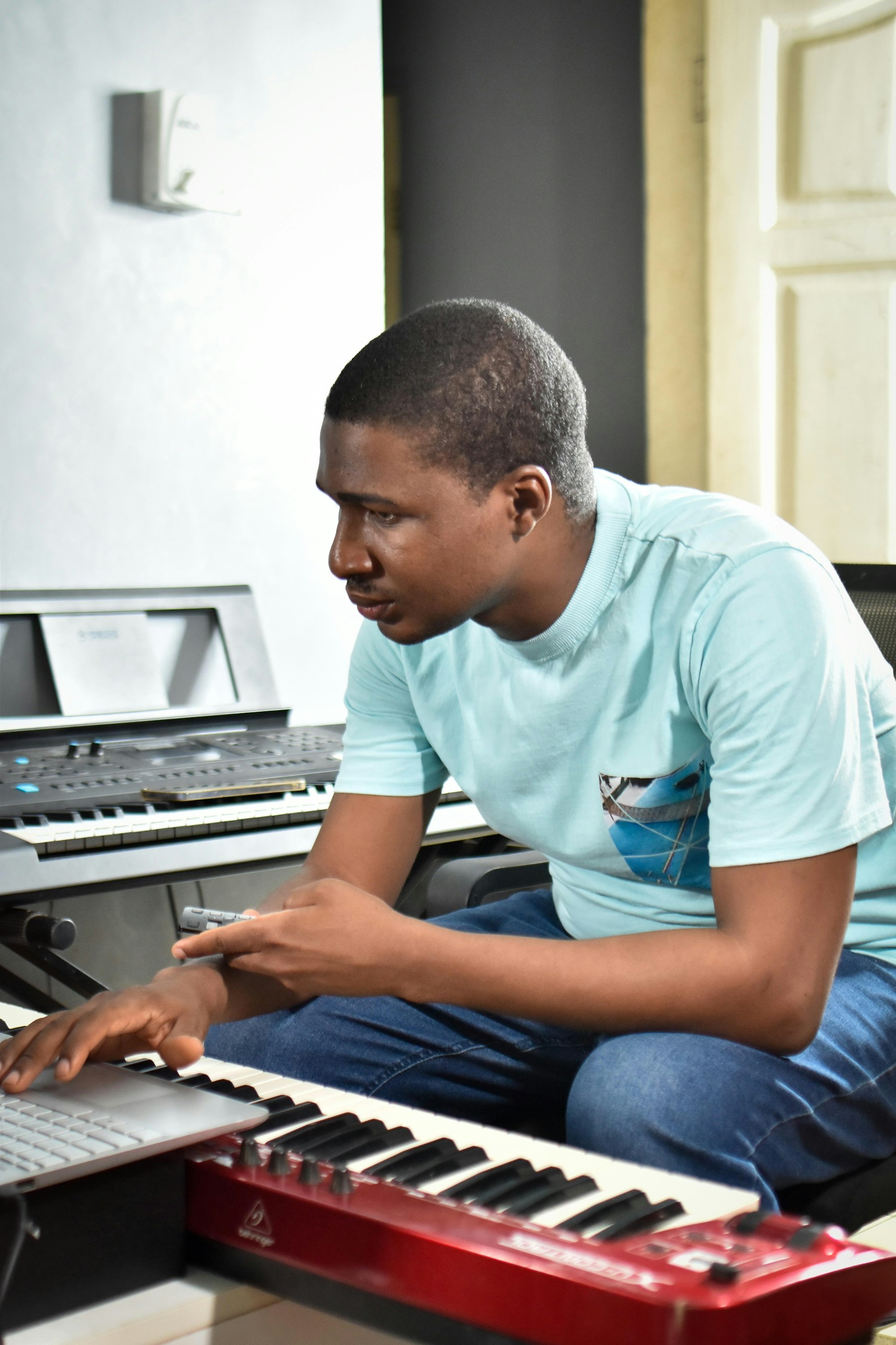 Musikproduzent arbeitet mit Keyboard und Laptop an einem eigenen Beat