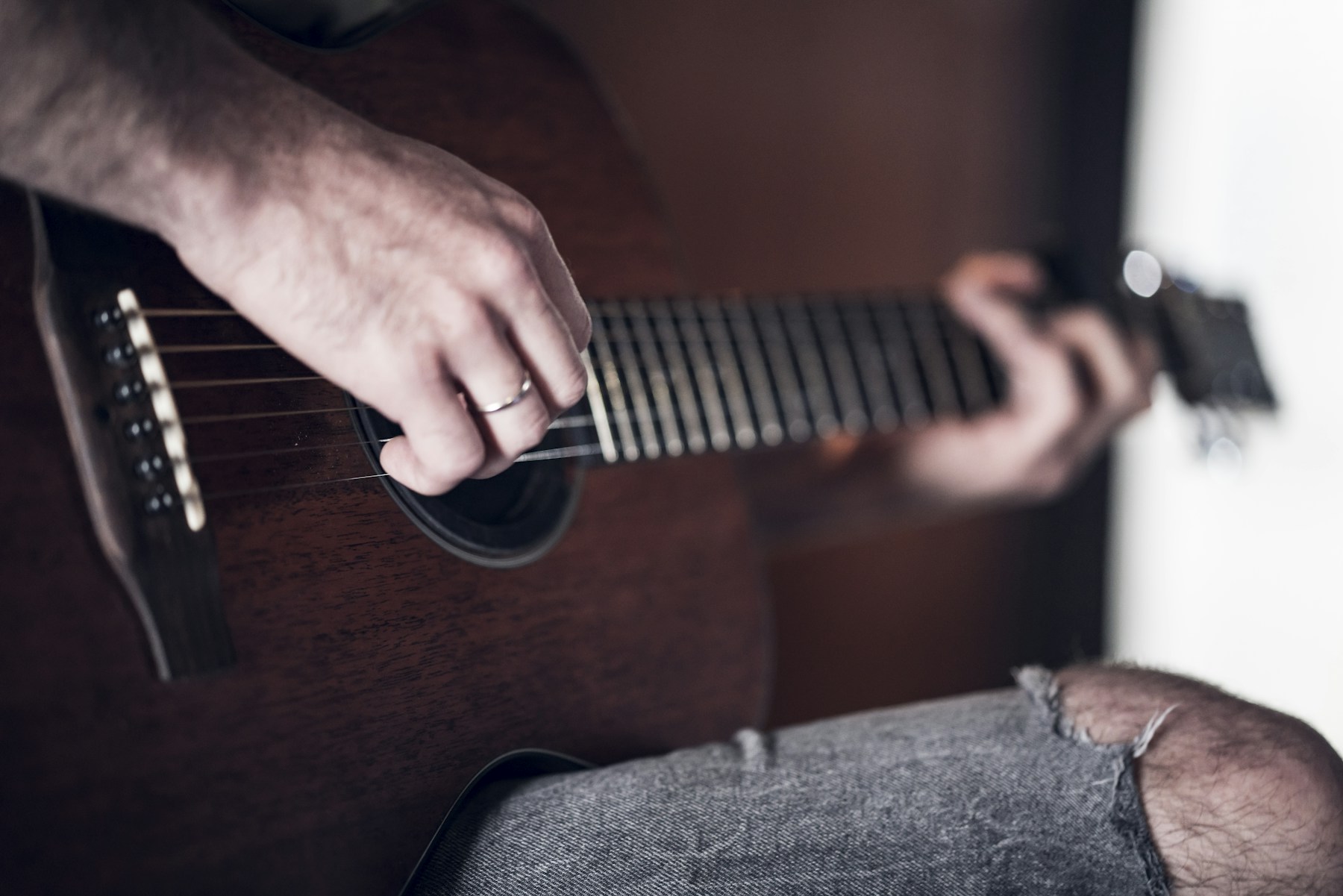 Person spielt zu Hause akustische Gitarre – ein persönlicher musikalischer Anfang als Geschenk