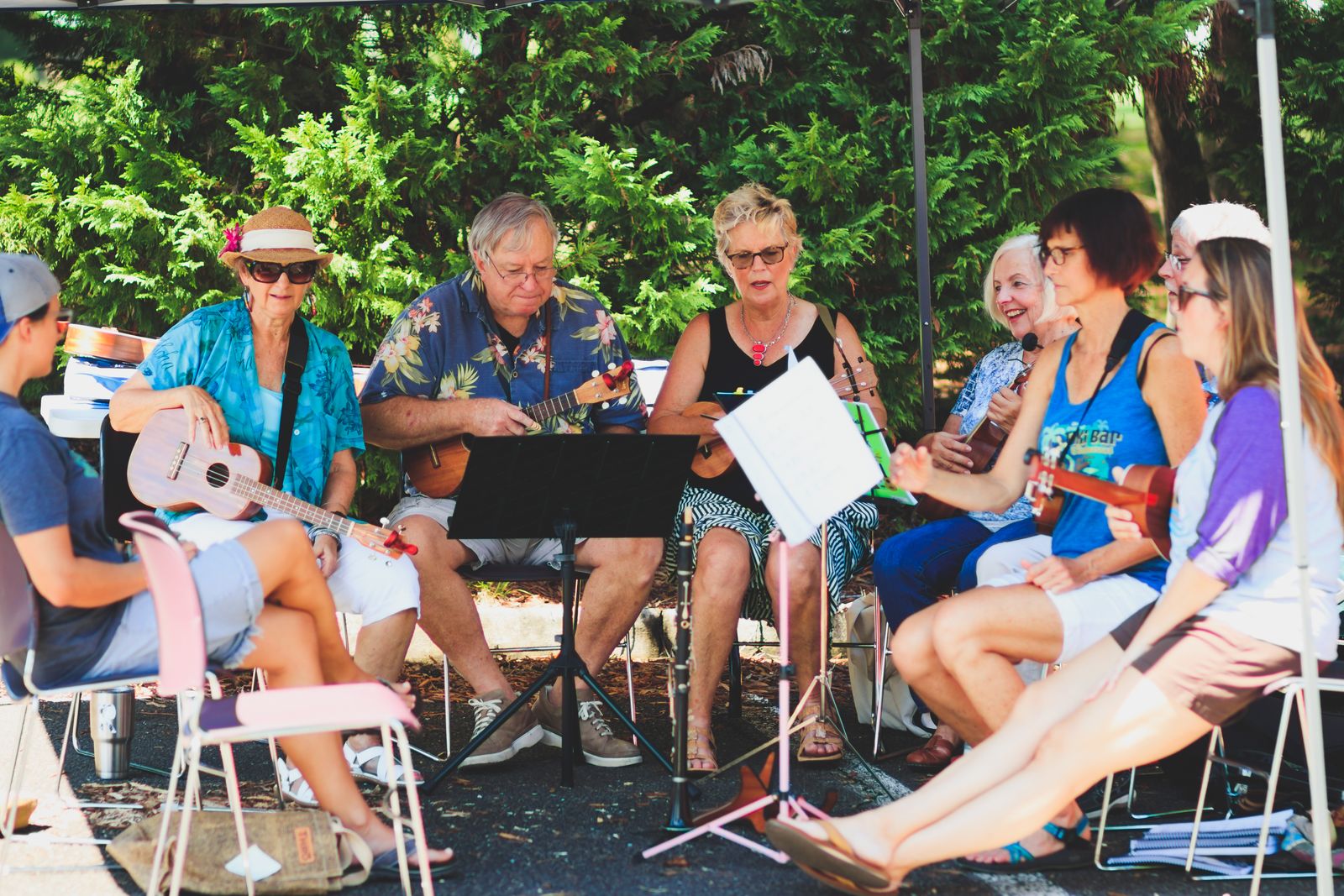 Mehrere Erwachsene spielen gemeinsam Ukulele in einer entspannten Runde